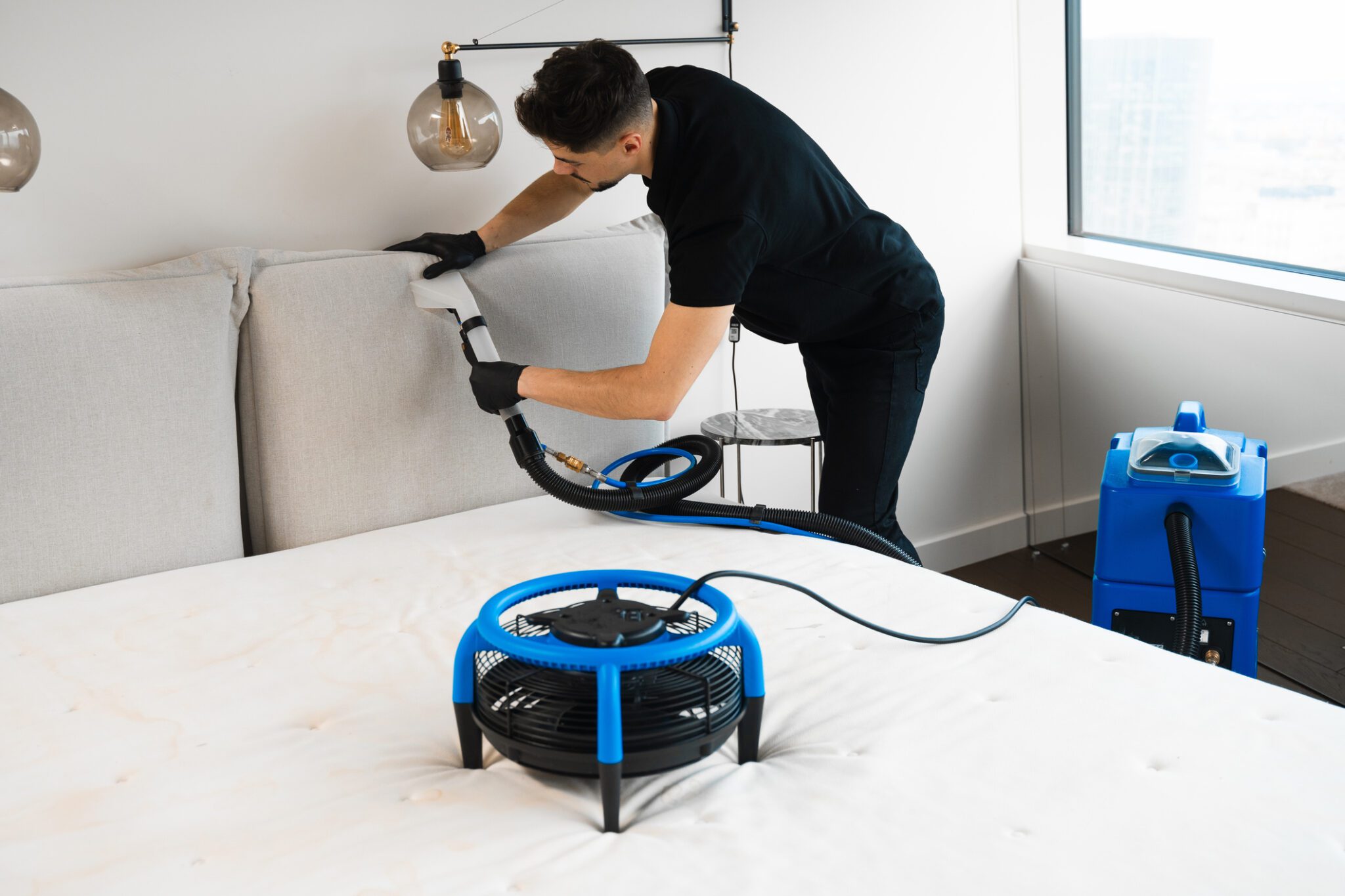 Person cleaning a mattress with professional equipment.