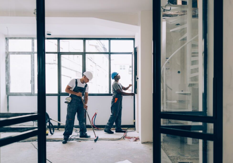 Two colleagues doing construction work together in an unfinished building.